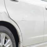 Car paint scratched at the door and the rubber out of focus.