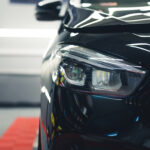 Portrait of a sports car with black car paint. Car detailing studio concept. Car lovers. Front view. Indoor shot. High quality photo
